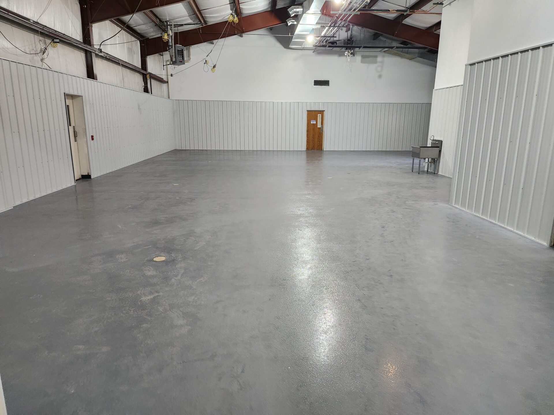 Spacious industrial warehouse interior with grey flooring.