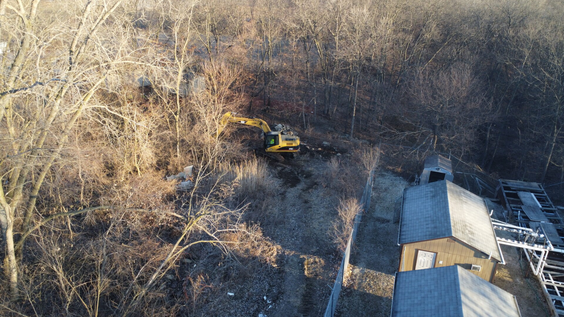 Aerial view of yellow excavator in a barren forest.