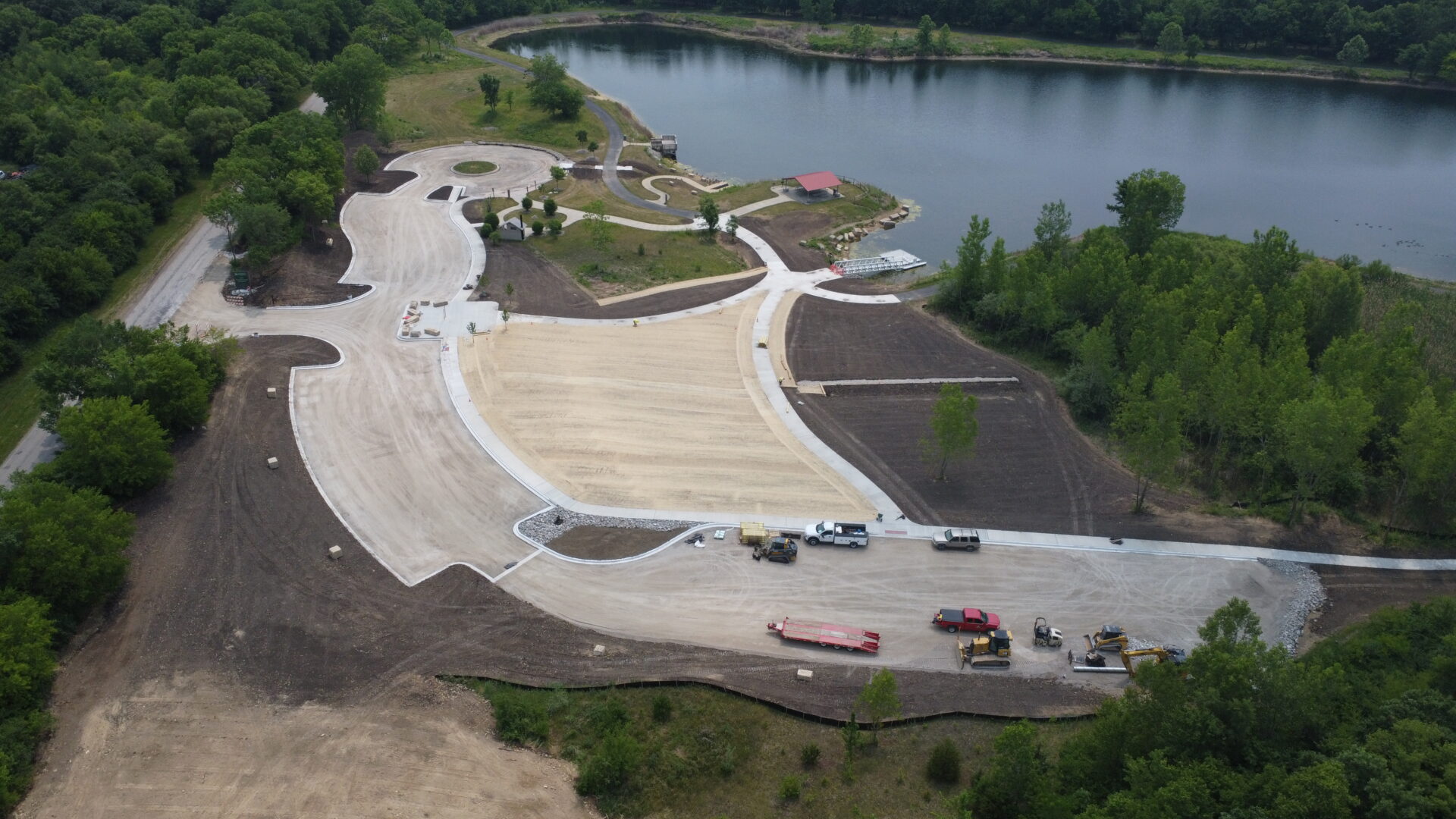 Aerial view of construction site near lake with vehicles.