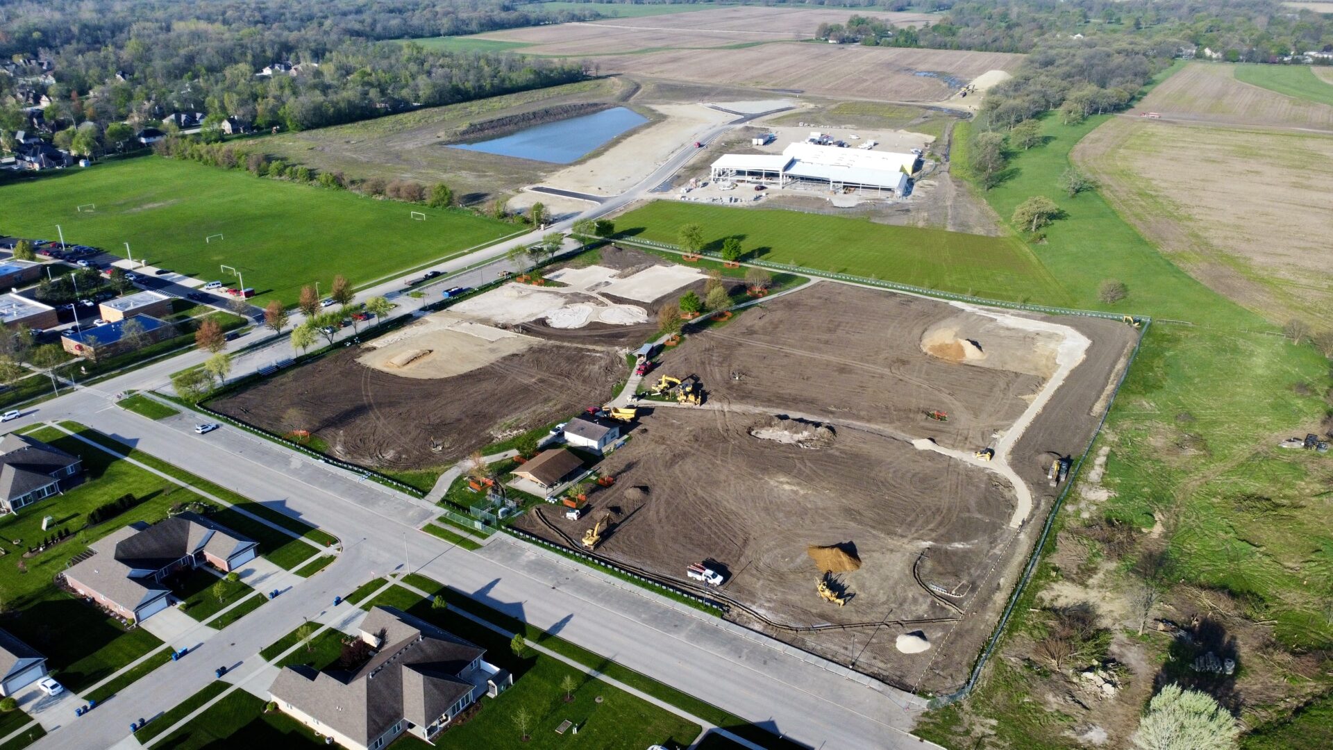 Aerial view of suburban construction site and green fields.